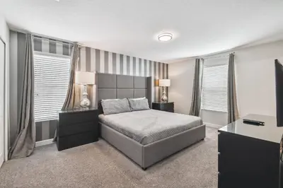 a bedroom with a bed and two windows at Luxury Family Retreat Near Disney in Kissimmee