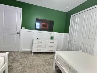 a bedroom with green walls and a bed and a tv at Orlando Luxury Stay Near Disney Parks in Kissimmee