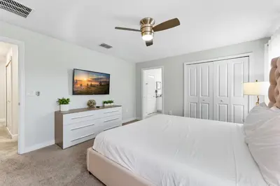 a white bedroom with a bed and a ceiling fan at Orlando Stay Near Disney with Private Pool in Kissimmee