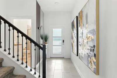 a hallway with white walls and a staircase with framed art at Luxury Family Stay Near Disney in Kissimmee