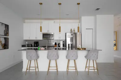 a kitchen with white cabinets and a counter with stools at Luxury Family Stay Near Disney in Kissimmee