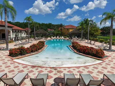 a pool at a resort with chairs and palm trees at Family Townhome w Private Pool Orlando in Kissimmee
