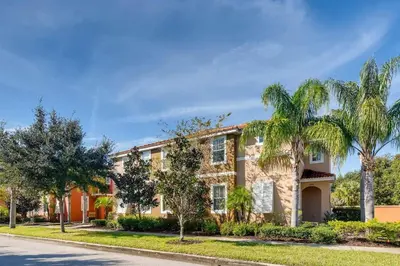 a house with palm trees in front of a street at Family Townhome w Private Pool Orlando in Kissimmee