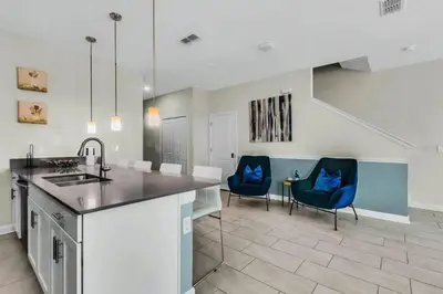 a kitchen with a sink and two blue chairs at Heated Pool 5-Star Amenities Near Disney in Kissimmee
