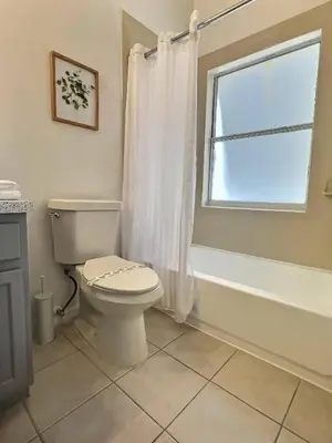 a bathroom with a toilet and a tub and a window at Family Villa near Disney – 15 Min in Kissimmee