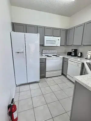 a kitchen with white appliances and gray cabinets at Family Villa near Disney – 15 Min in Kissimmee
