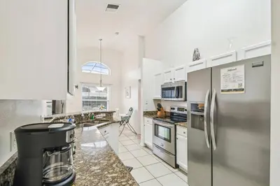 a kitchen with white cabinets and a stainless steel refrigerator at 4BR Home Game Room in Lake Berkley in Kissimmee