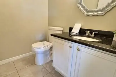 a bathroom with a toilet and a sink with a mirror at Montego Bay Retreat w Pool in Kissimmee