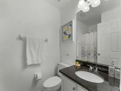 a white bathroom with a toilet and a sink at Spacious Home · Near Disney Parks in Kissimmee