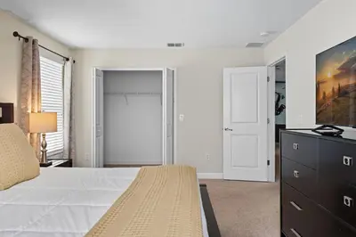 a bedroom with a bed and a dresser and a television at Spacious 6BR Pool Resort - Near Disney in Kissimmee