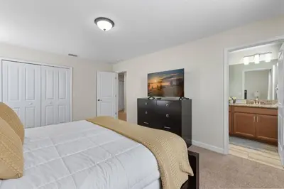 a bedroom with a bed and a bathroom with a sink at Spacious 6BR Pool Resort - Near Disney in Kissimmee