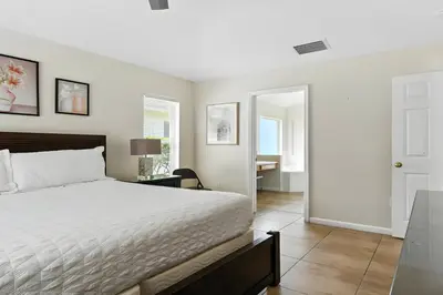 a bedroom with a bed and a desk and a door at Cozy No-Carpet Home Heated Pool Disney in Kissimmee