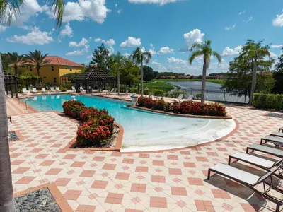 a swimming pool at a resort with chairs and flowers at Family Getaway wPvt Pool close to Disney in Kissimmee