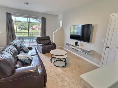 a living room with a leather couch and a television at Family Getaway wPvt Pool close to Disney in Kissimmee