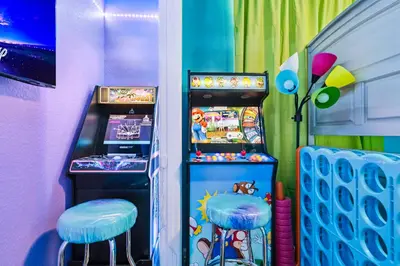 a room with a pinball machine and two stools at 3BR Windsor Hills Condo Water Park and Skeeball Near Disney No Resort Fees in Orlando