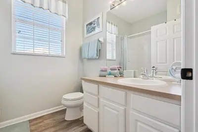 a white bathroom with a sink and a toilet at 3BR Windsor Hills Condo Water Park and Skeeball Near Disney No Resort Fees in Orlando