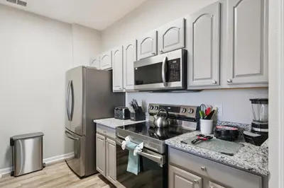 a kitchen with white cabinets and a stainless steel refrigerator at 3BR Windsor Hills Condo Water Park and Skeeball Near Disney No Resort Fees in Orlando