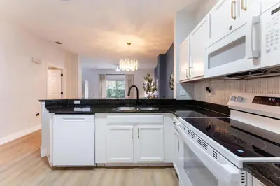 a kitchen with white cabinets and a black counter top at Family Townhouse 10 Min to Parks with Themed Room in Kissimmee