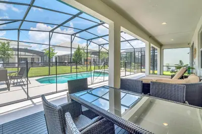 a patio with a glass table and chairs and a swimming pool at Spacious Disney-Area Home with Private Pool in Kissimmee