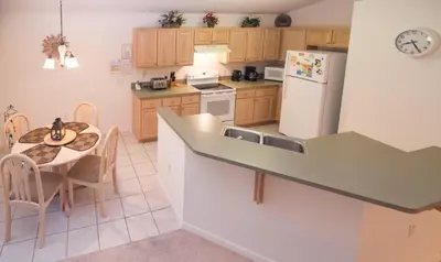 a kitchen with a table and a white refrigerator at Cumbrian Retreat home in Kissimmee