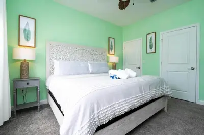 a bedroom with a large white bed with green walls at Casa 4Q Storey Lake c/ Quarto Temático & Piscina in Kissimmee