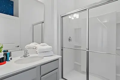 a white bathroom with a shower and a sink at Casa 6Q Paradiso Grande. Piscina + Sala de Jogos in Orlando