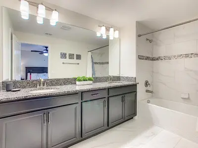 a bathroom with a sink and a tub and a mirror at 3065 - 5BR w Pool 10min Disney 2 Water Parks in Kissimmee