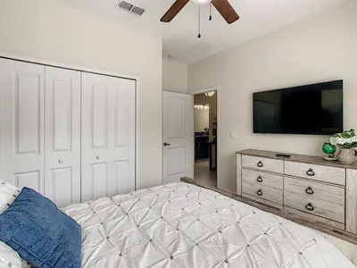 a bedroom with a bed and a flat screen tv at 3065 - 5BR w Pool 10min Disney 2 Water Parks in Kissimmee