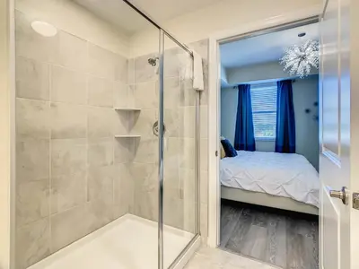 a bathroom with a glass shower with a bed at 4731#308- 3BR Condo 10min Disney 2 WaterParks in Kissimmee
