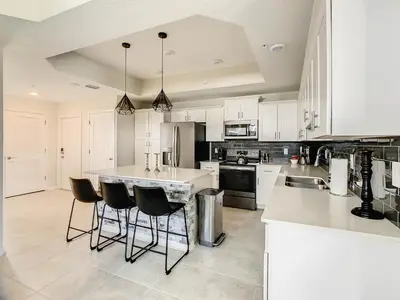 a kitchen with white cabinets and a island with bar stools at 4731#308- 3BR Condo 10min Disney 2 WaterParks in Kissimmee