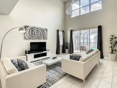a living room with two white couches and a tv at 4766 - 5BR w Pool 10min Disney 2 Water Parks in Kissimmee
