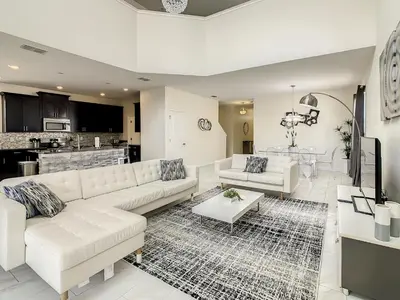 a living room with white furniture and a kitchen at 4766 - 5BR w Pool 10min Disney 2 Water Parks in Kissimmee
