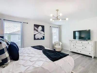 a bedroom with a bed and a flat screen tv at 4774 - 7BR w Pool 10min Disney 2 Water Parks in Kissimmee