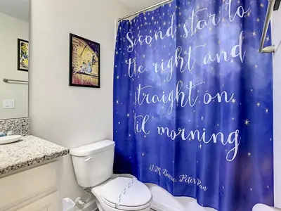 a bathroom with a blue shower curtain with the wordssecond star to the right at 4781 - 5BR w Pool 10min Disney 2 Water Parks in Kissimmee
