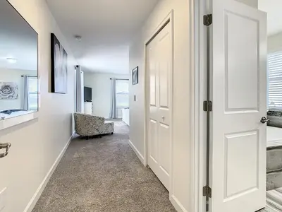 a hallway with a white door and a chair at 4781 - 5BR w Pool 10min Disney 2 Water Parks in Kissimmee