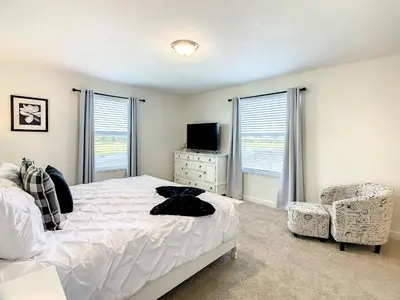 a bedroom with a bed and a tv and a chair at 4809 - 5BR w Pool 10min Disney 2 Water Parks in Kissimmee