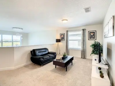a living room with a black leather chair and a television at 4809 - 5BR w Pool 10min Disney 2 Water Parks in Kissimmee