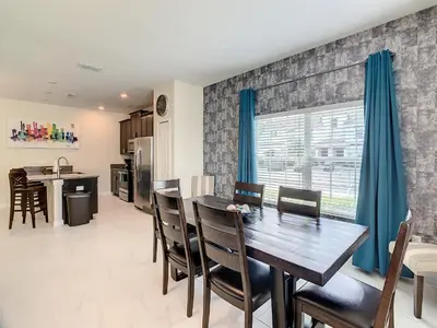a kitchen and dining room with a wooden table and chairs at 4874 - 5BR w Pool 10min Disney 2 Water Parks in Kissimmee