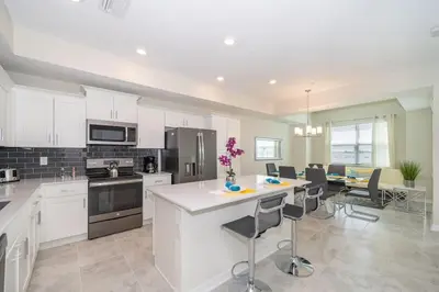 a kitchen with white cabinets and a table with chairs at Lake View Condo Near Disney in Kissimmee