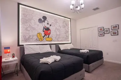 a bedroom with two beds and a painting of mickey mouse at Veranda Palms 6BR Pool Near Disney Parks in Kissimmee