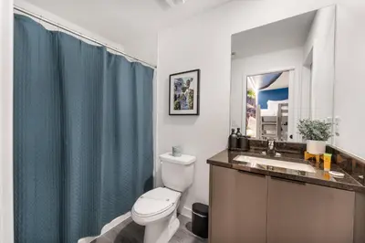 a bathroom with a toilet and a sink with a blue shower curtain at Family 3BR Home Minutes from Disney in Kissimmee