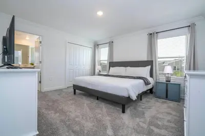 a white bedroom with a bed and a television at 4BR Pool Home at Storey Lake Near Disney in Kissimmee