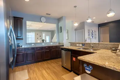 a large kitchen with wooden cabinets and a large mirror at 6BR Home w Theater Pool Near Disney in Orlando