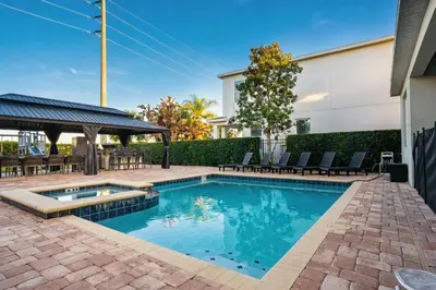 a swimming pool in a yard with chairs and a building at 6BR Home w Theater Pool Near Disney in Orlando