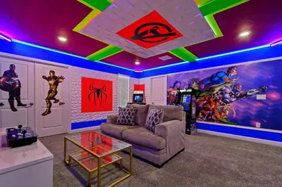 a living room with a couch and a marvel mural at Spacious 9BR w Pool Theater at Storey Lake in Kissimmee