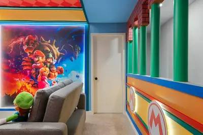 a child sitting in a chair in a room with a mural at 3BR Home w Game Room Near Disney in Kissimmee