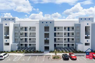 a large white building with cars parked in a parking lot at Vibrant Family Condo -10 Min From Disney in Kissimmee