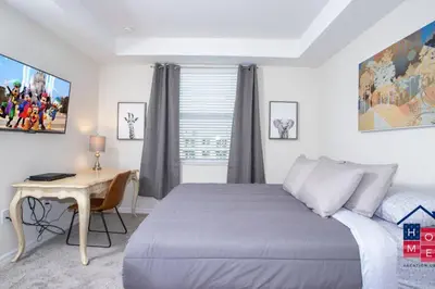 a bedroom with a bed and a desk and a window at Stunning Condo in the Heart of Orlando in Kissimmee