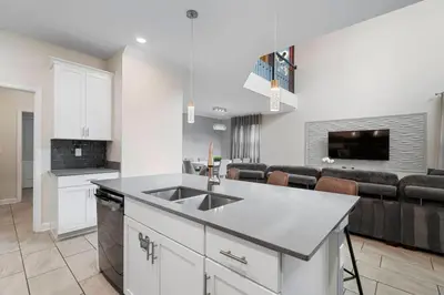 a kitchen with a sink and a living room at Casa 5Q Storey Lake –10 min da Disney in Kissimmee