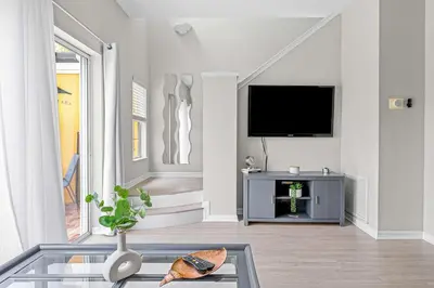 a living room with a tv and a glass table at Elegant Townhome with Water View in Kissimmee